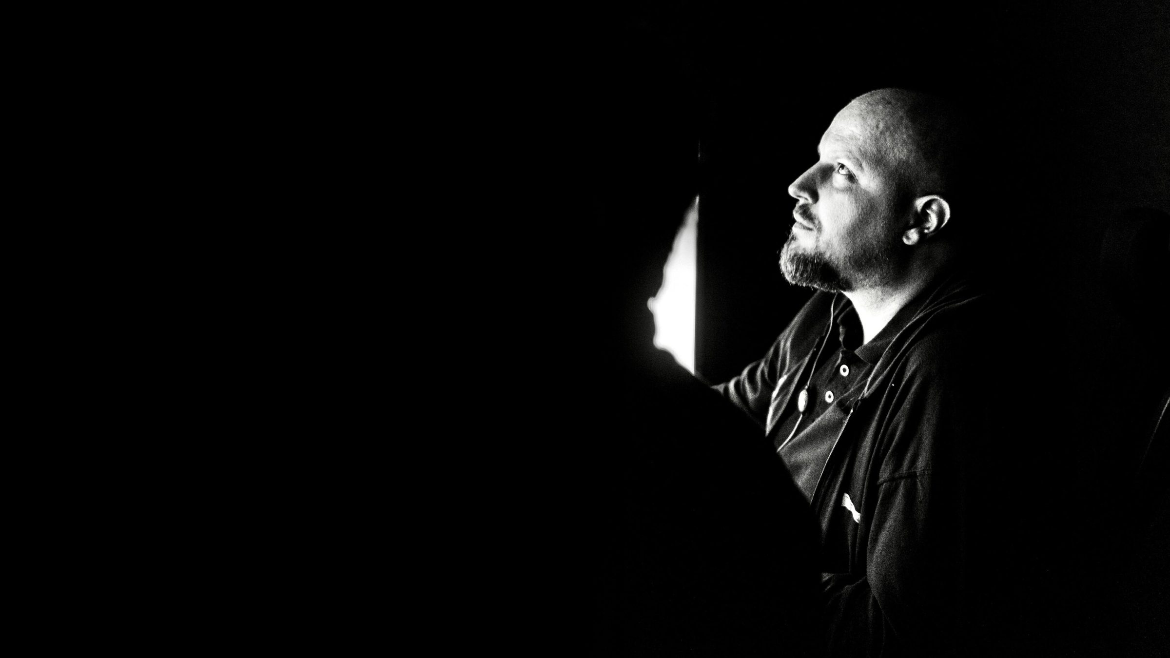 Miguel Fuentes en blanco y negro, de perfil, mirando hacia arriba iluminado por una luz lateral